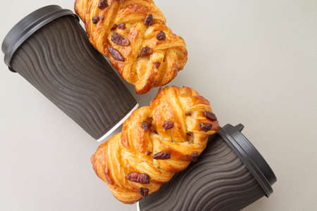 Coffee to go concept. Disposable black cup with spiral texture with black plastic cover and maple pecan on a trendy grey background. Place for text. Flat lay style. Top viewの写真素材