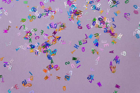 Multicolored sparkle glitter confetti letters on lilac for party or festive background. Holiday and fun conceptの写真素材
