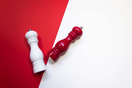 White and red salt and pepper wooden grinders mill on red and white colorblock background. Gourmet spicy cooking concept. Flat lay style. Place for textの写真素材