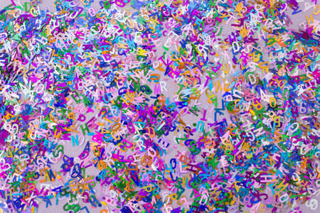 Multicolored sparkle glitter confetti letters on lilac for party or festive background. Holiday and...