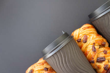 Coffee to go concept. Disposable black cup with spiral texture with black plastic cover and maple pecan on a trendy grey background. Place for text. Flat lay style. Top viewの写真素材