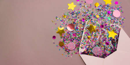 Banner with opened white envelope with multicolored sparkle glitter confetti letters on pastel lilac background. Festive greeting concept. Flat lay style. Top view. Place for text.の写真素材