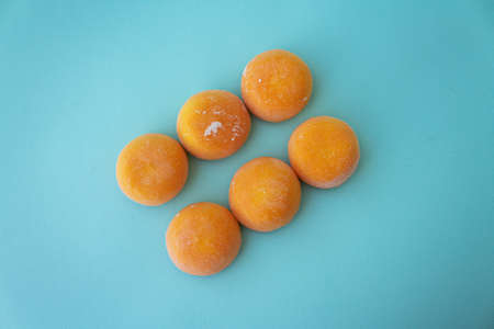 Mochi with mango. Premium ice-cream wrapped in sweet rice dough, traditional japonese desert. Gluten Free. Orange on pastel blue.の写真素材