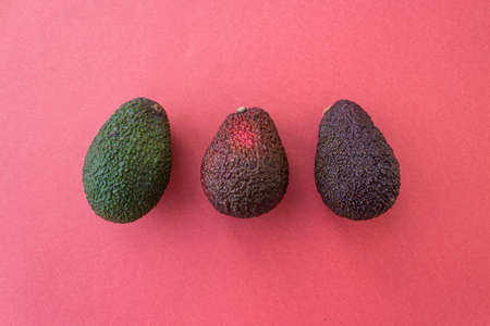 Avocado in different degrees of ripeness on a red background. Flat lay style. Close up. Place for text.の写真素材
