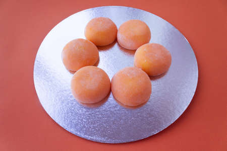 Mochi with mango. Premium ice-cream wrapped in sweet rice dough, traditional japonese desert. Gluten Free. Orange on pastel blue.の写真素材