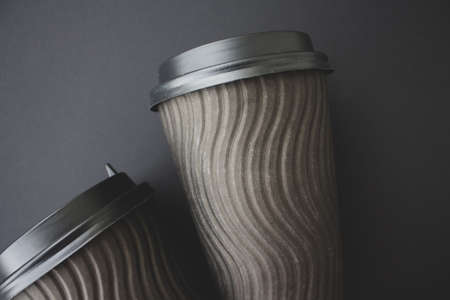 Coffee to go concept. Disposable black cup with spiral texture with black plastic cover on a black background. Monochrome. Place for text. Flat lay style. Top viewの写真素材
