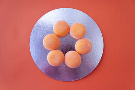 Mochi with mango. Premium ice-cream wrapped in sweet rice dough, traditional japonese desert. Gluten Free. Orange on pastel blueの写真素材
