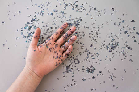 Girl hand with shiny black confetti letters on grey background. Concept of text creator - writer, journalist, copywriter, bloggerの写真素材