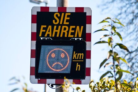 Digital speed limit sign in germany shows car driver speed measurement. (Translation "you drive ... mp / h") Driver can see in Display his Speed and a Smiley under limit or a sad face by driving too fastの写真素材