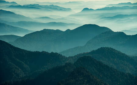 View of Himalayas mountain range with visible silhouettes through the colorful fog from Khalia top trek trail. Khalia top is at an altitude of 3500m himalayan region of Kumaon, Uttarakhand, India.の写真素材