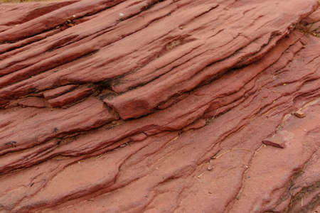 Sandstone forms when layers of sand accumulates by sedimentation are compacted & cemented by precipitation of minerals within pore spaces of sand grains. Red color is imparted by Hematite Iron oxide.の写真素材
