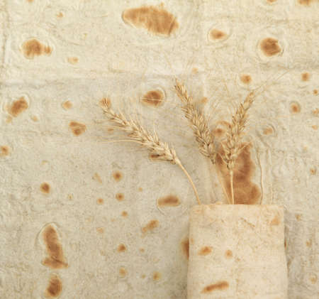 Background texture of baked lavash bread and ears of wheat の写真素材