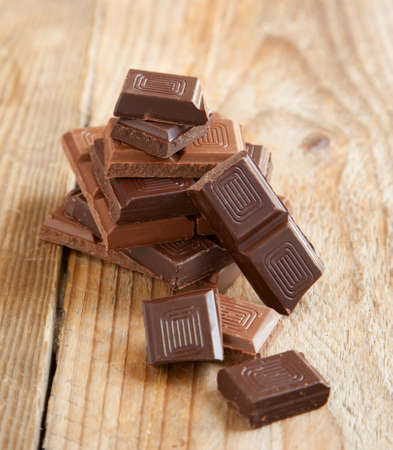 Broken chocolate bar on wooden background  Selective focus
