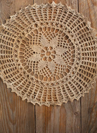 Old handmade crochet doily over wooden background