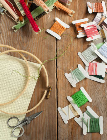 Cross-stitch set  colour palette, threads, canvas against a wooden backgroundの写真素材