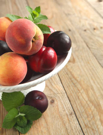 Fresh peaches, nectarines and plums in vaseの写真素材