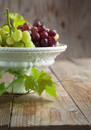 Grapes in vase on a wooden tableの写真素材