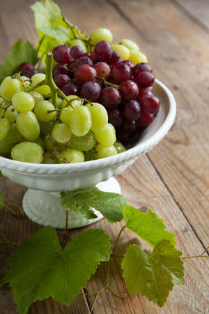 Grapes in vase on a wooden tableの写真素材