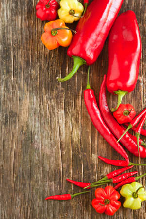 Colorful sweet peppers and hot chili peppers on wooden backgroundの写真素材