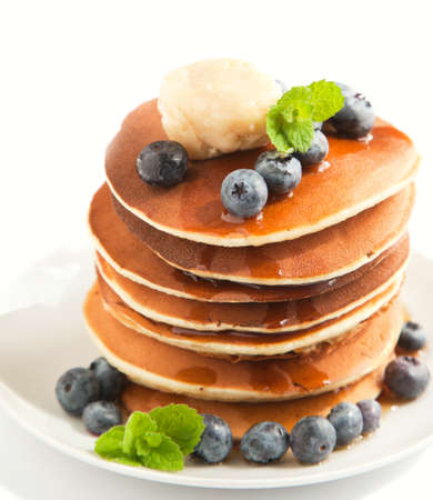 Stack of pancakes with fresh blueberry, maple butter and syrup isolated on whiteの写真素材