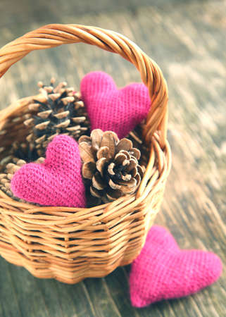 Pine cones and handmade crochet hearts in basketの写真素材