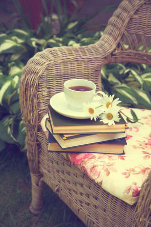 Cup of tea with a books and chamomiles on a chairの写真素材