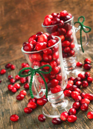 Ripe cranberries in glass cup on wooden backgroundの写真素材