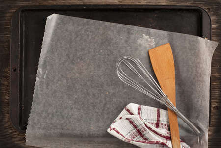 Old metal baking pan with paper and kitchen utensilsの写真素材