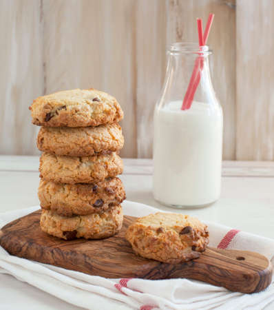 Chocolate chip cookies on cooking board and bottle of milk の写真素材