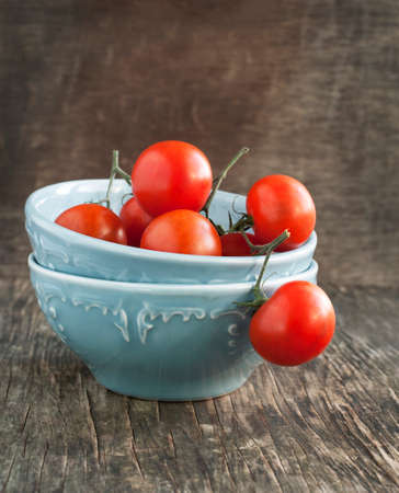 Fresh tomatoes in bowl on woden tableの写真素材