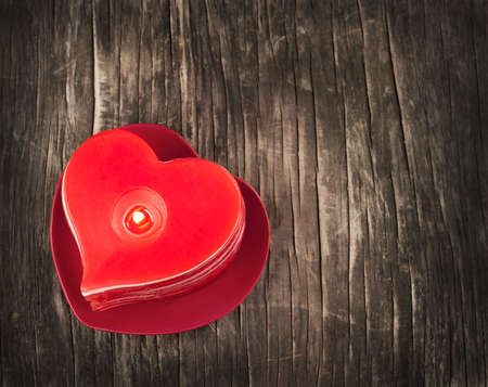 Red burning heart shaped candles on wooden background の写真素材