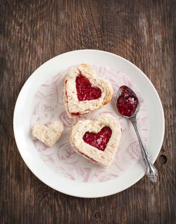 Heart shape sandwich with strawberry jam on a plateの写真素材
