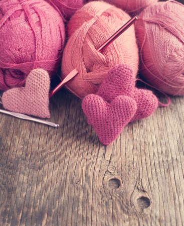 Crochet pink hearts  and yarn on wooden の写真素材