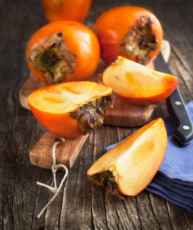Fresh ripe persimmons on a wooden tableの写真素材