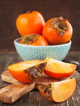 Fresh ripe persimmons on a wooden tableの写真素材