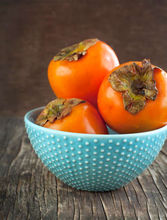 Fresh ripe persimmons on a wooden tableの写真素材