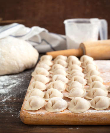 Russian traditional pelmeni with meat  Uncooked freshly made raw meat pelmeni on a wooden board  の写真素材
