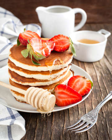 Stack of pancakes with strawberry and honeyの写真素材