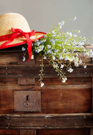 Blue summer flowers and straw hat on old vintage chest の写真素材