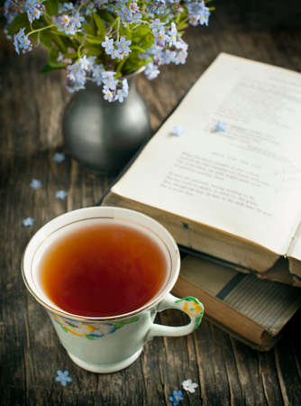 Cup of tea, vintage books and  summer blue flowers on the table  Toned image の写真素材
