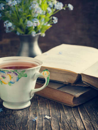 Cup of tea, vintage books and  summer blue flowers on the table  の写真素材