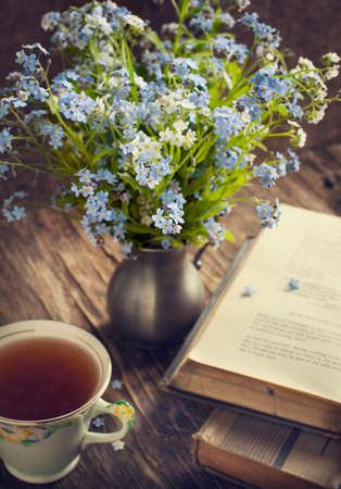 Cup of tea, vintage books and  summer blue flowers on the table  の写真素材