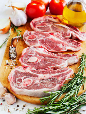 Raw lamb cutlets with vegetables, herbs and spices on wooden chopping boardの写真素材