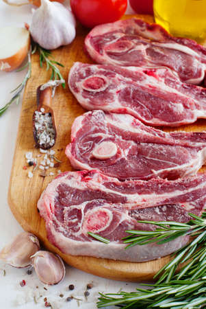 Raw lamb cutlets with vegetables, herbs and spices on wooden chopping boardの写真素材