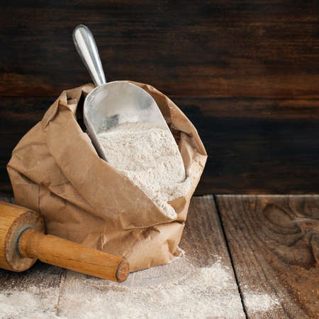 Rye flour in brown paper bag on wooden background.の写真素材