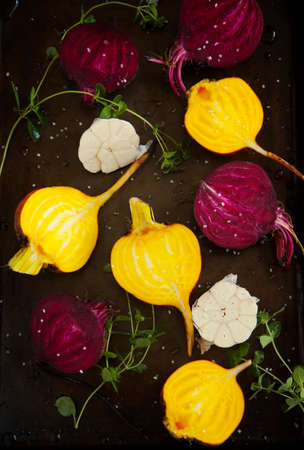 Preparing raw beetroots and garlic for roasting on a baking trayの写真素材