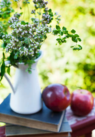 Summer wild flowers in glass vase, old books and apples. Shallow depth of field. Selective focusの写真素材