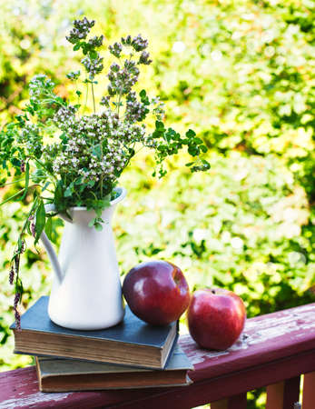 Summer wild flowers in glass vase, old books and apples. Shallow depth of field. Selective focusの写真素材
