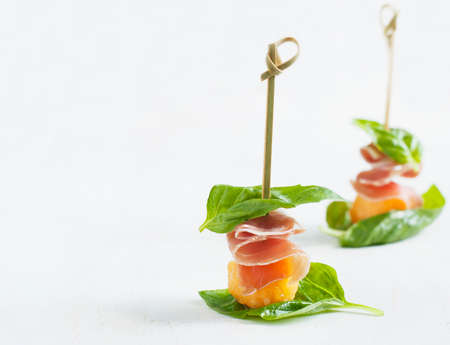 Appetizer with melon and prosciutto on skewersの写真素材