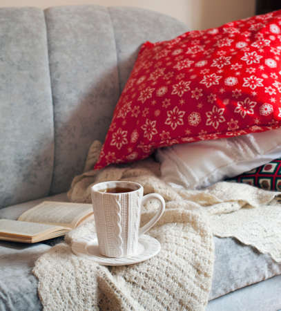 Still life interior details, cup of tea and book on the sofa with pillowsの写真素材